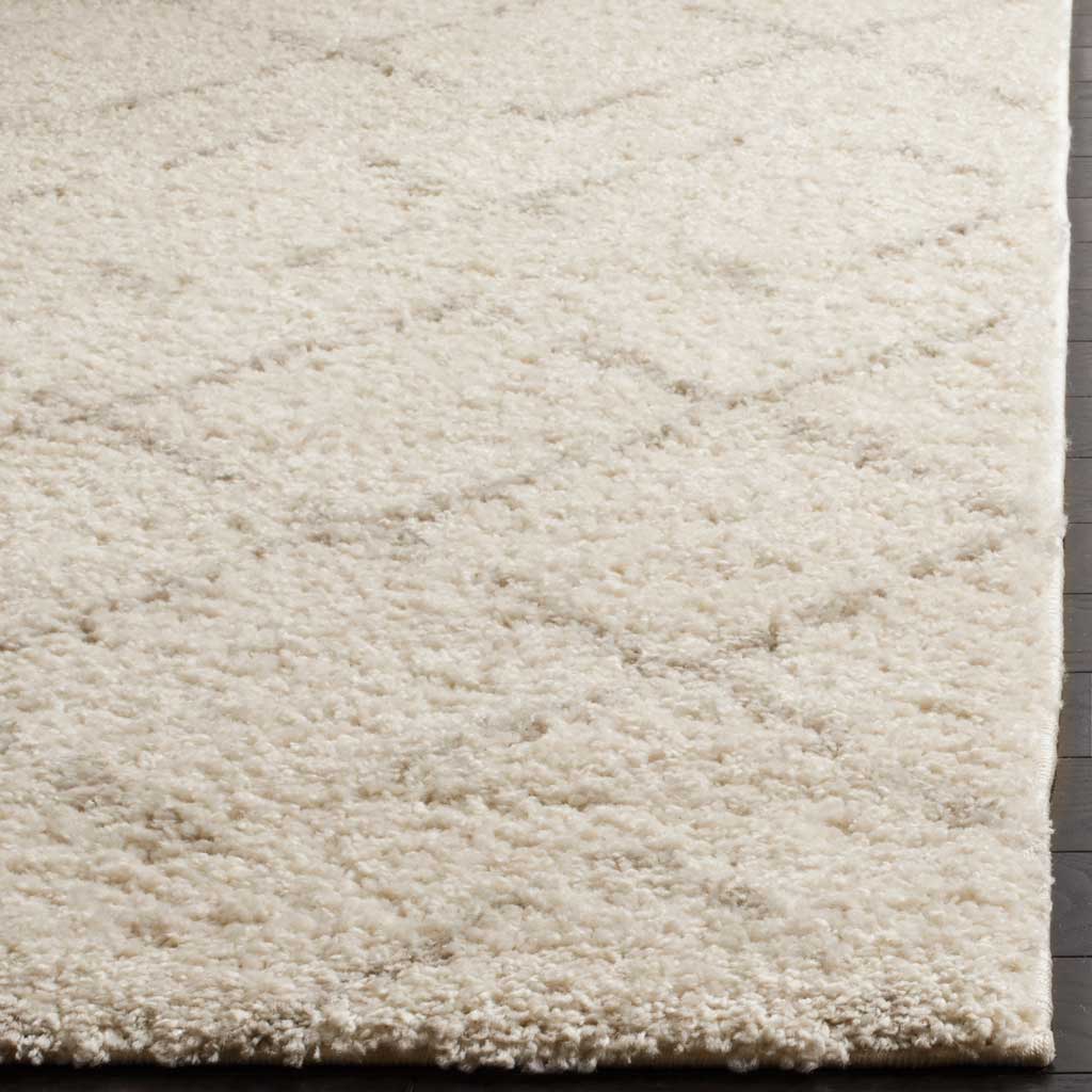 Soft ivory fibers and faint beige patterning meet at the rug's cushioned, bound edge.