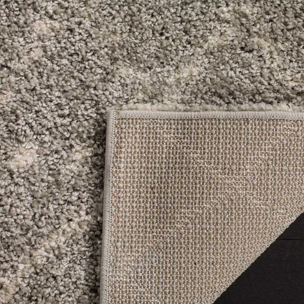 Neutral woven backing and secured binding lie beneath the rug's lofty gray pile.