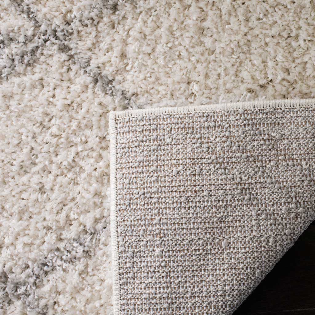 Closely woven backing and a secured border sit beneath fluffy ivory and gray pile.