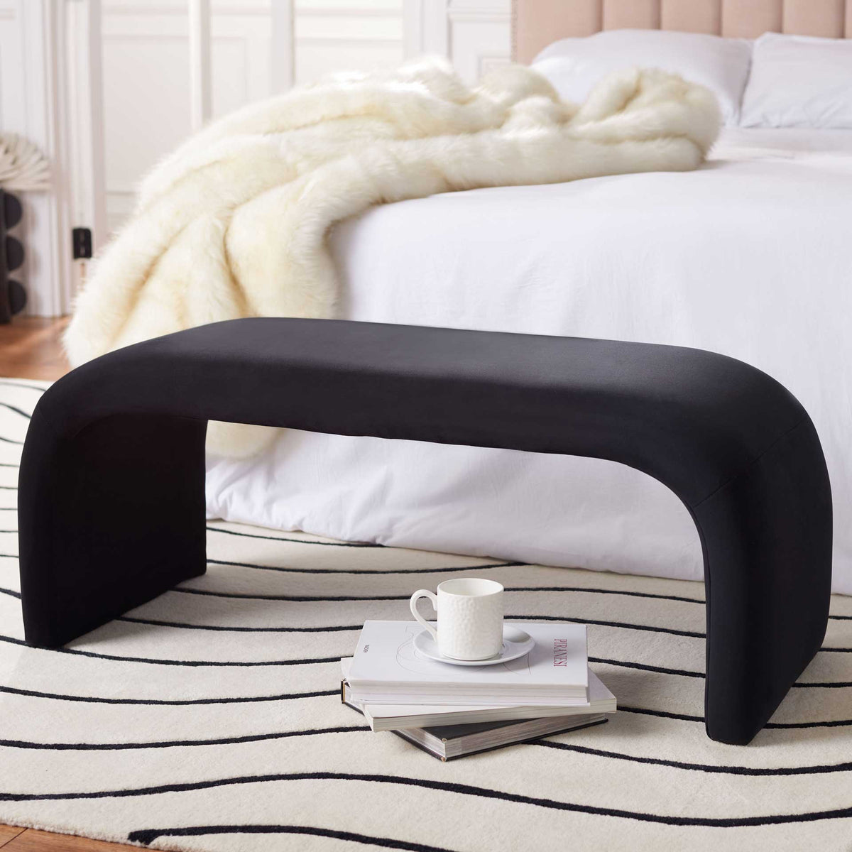A black velvet bench adds a sculptural accent at the foot of a bed.