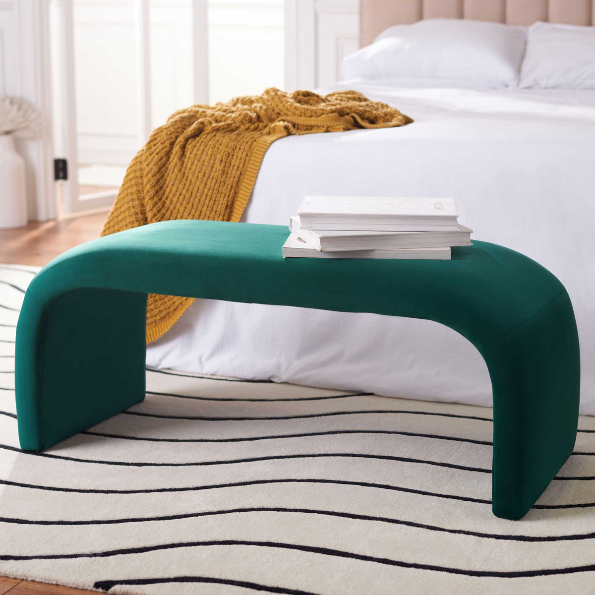 An emerald velvet bench brings a rich green accent to a bright bedroom.