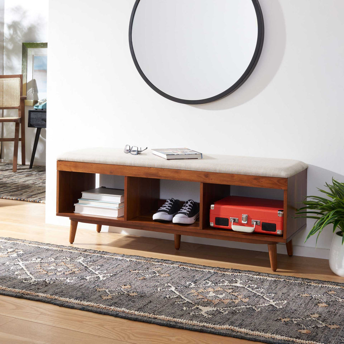 Books and shoes tuck beneath the padded cream seat of this versatile wood bench