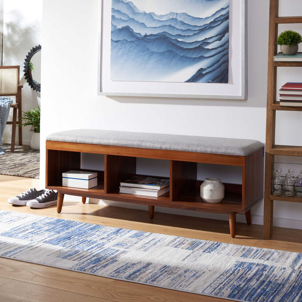 Gray-cushioned wood bench offers easy-access storage for books and decor in three open cubbies