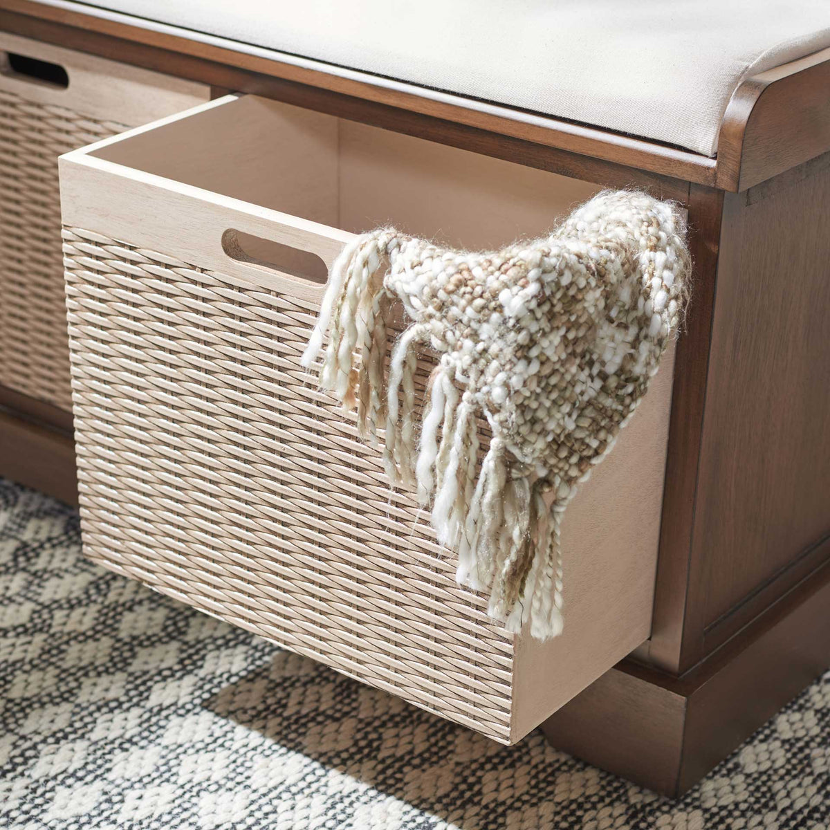 A pullout woven basket keeps folded throws close at hand under the cushioned brown bench.