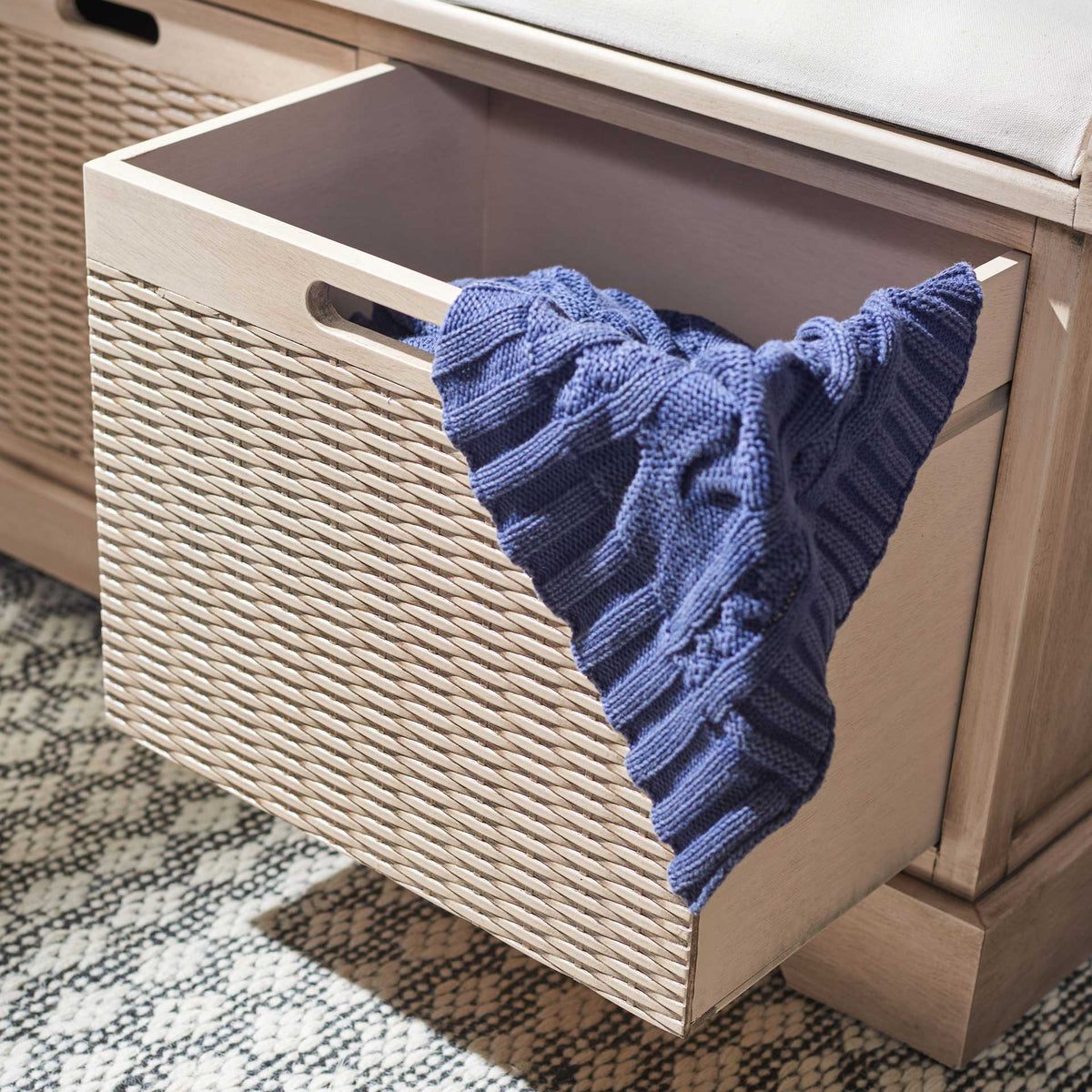 A deep woven basket drawer opens to stow a throw under the padded bench seat.