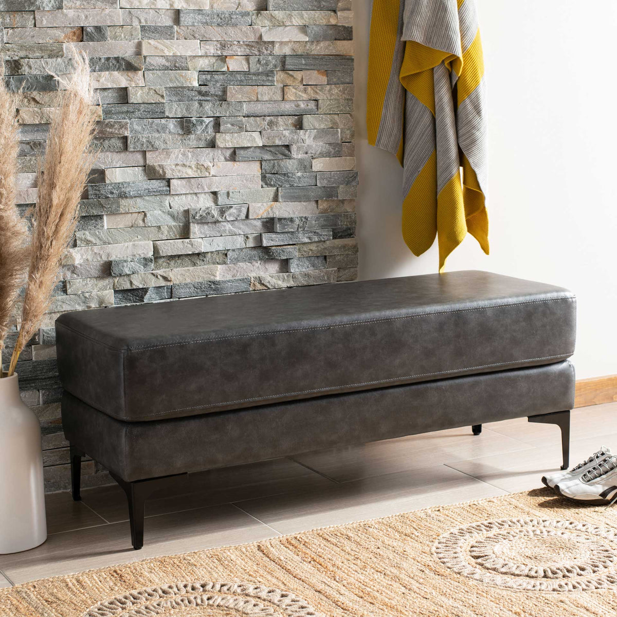 Plush charcoal upholstery and slender black legs create an inviting entryway accent