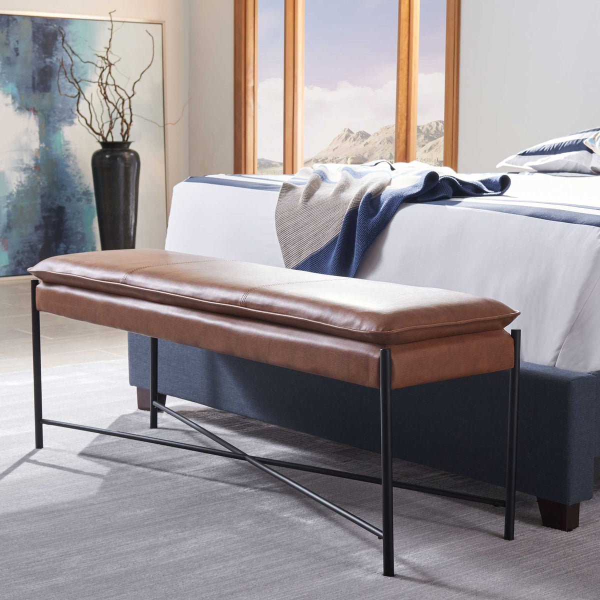 Brown cushioned bench adds streamlined seating and black X-braced accents at the foot of a bed