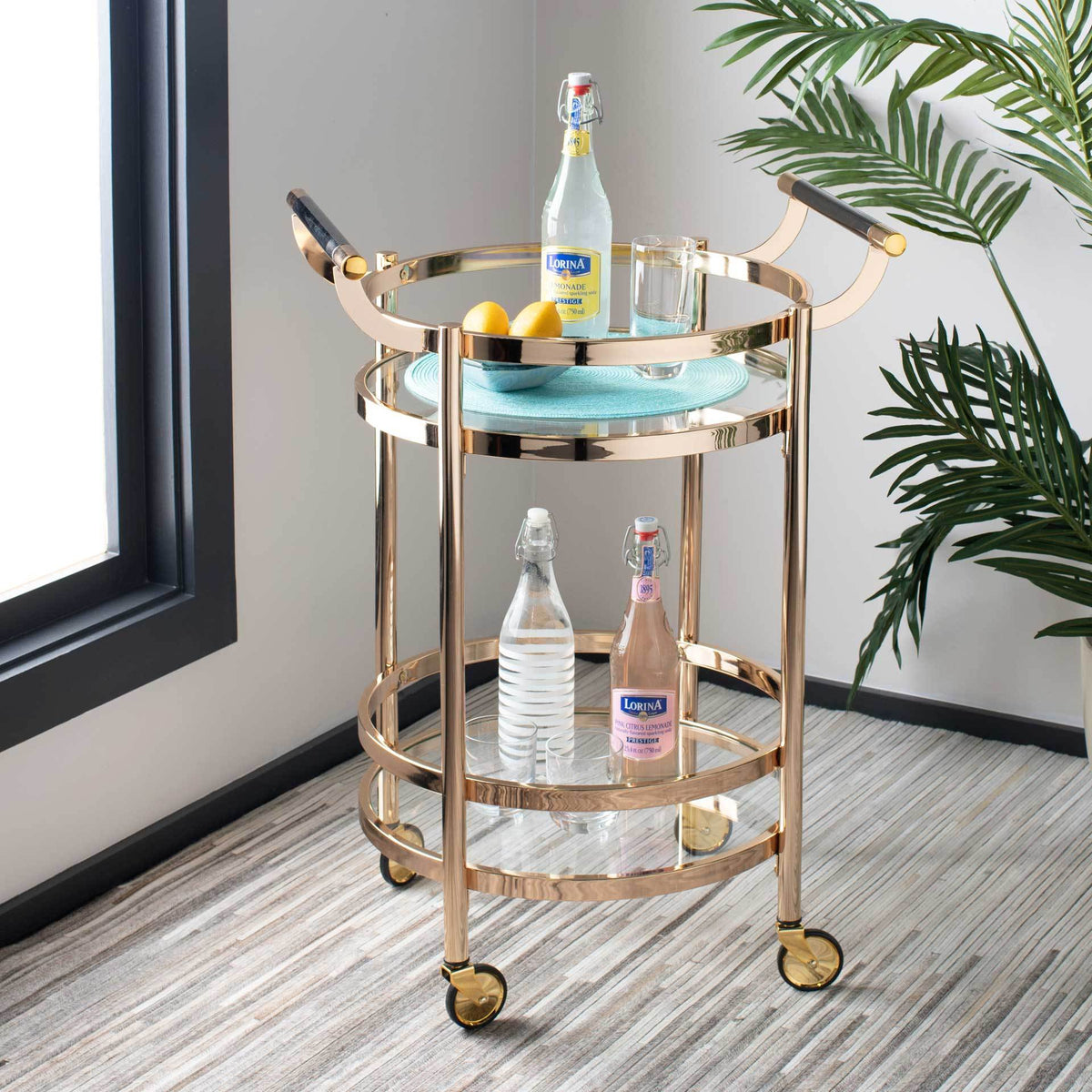 This gold bar cart presents refreshments on two glass tiers, ready to roll where needed