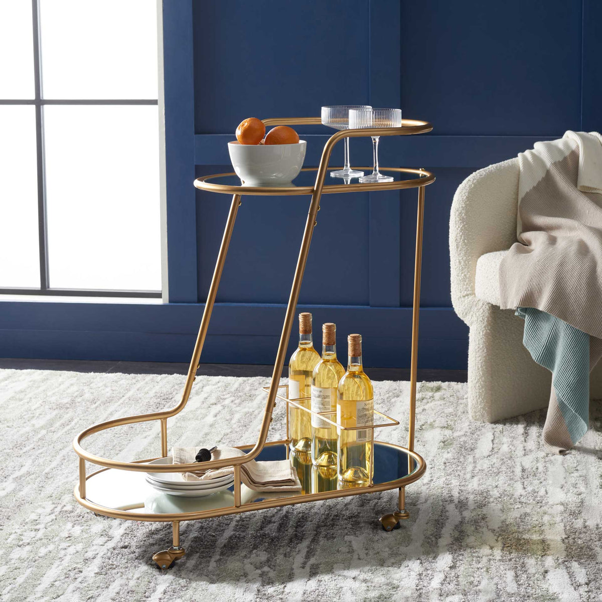 Mirrored tiers display bottles and glassware beneath the bar cart's champagne gold rails.