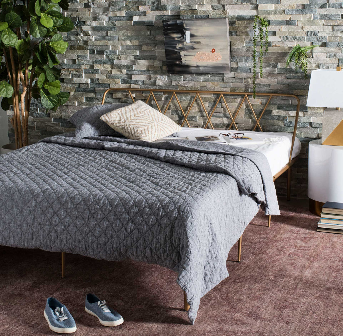 Gold lattice headboard complements a bed layered in textured gray bedding