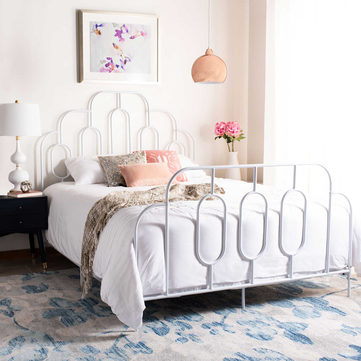 White metal bed with sculptural arches and oval details amid soft layered bedding