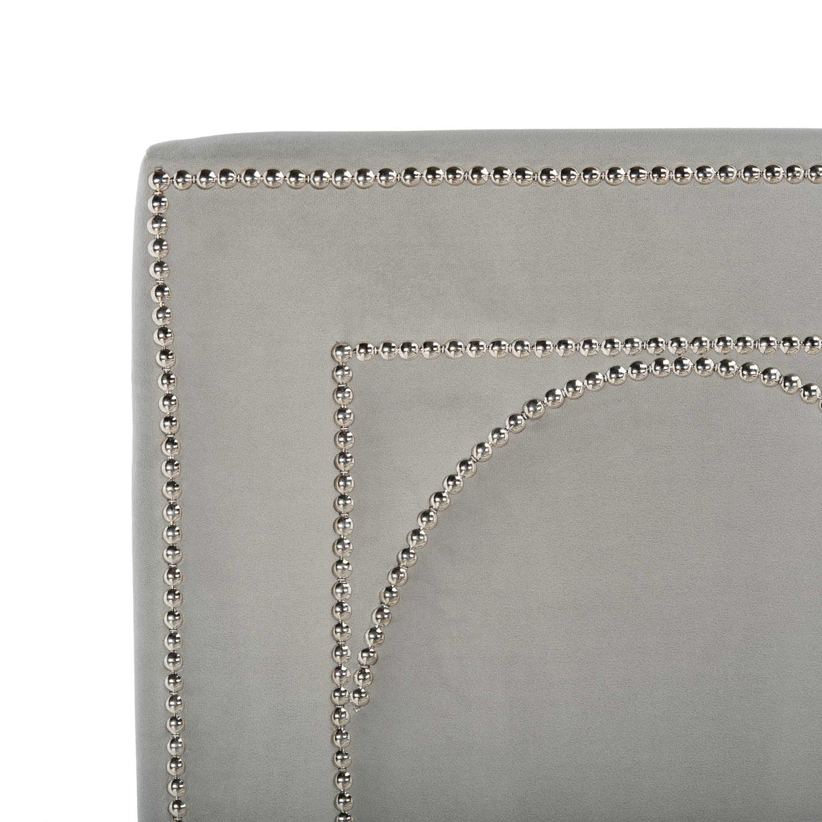 Gleaming nailheads trace curved arches across a soft gray velvet headboard