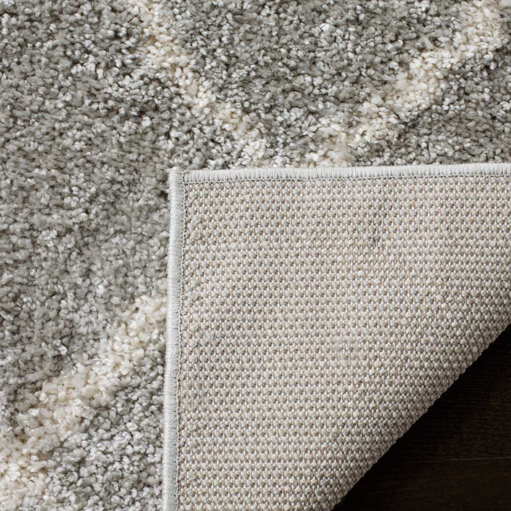 Folded light gray shag reveals a tightly woven underside beneath the cream design
