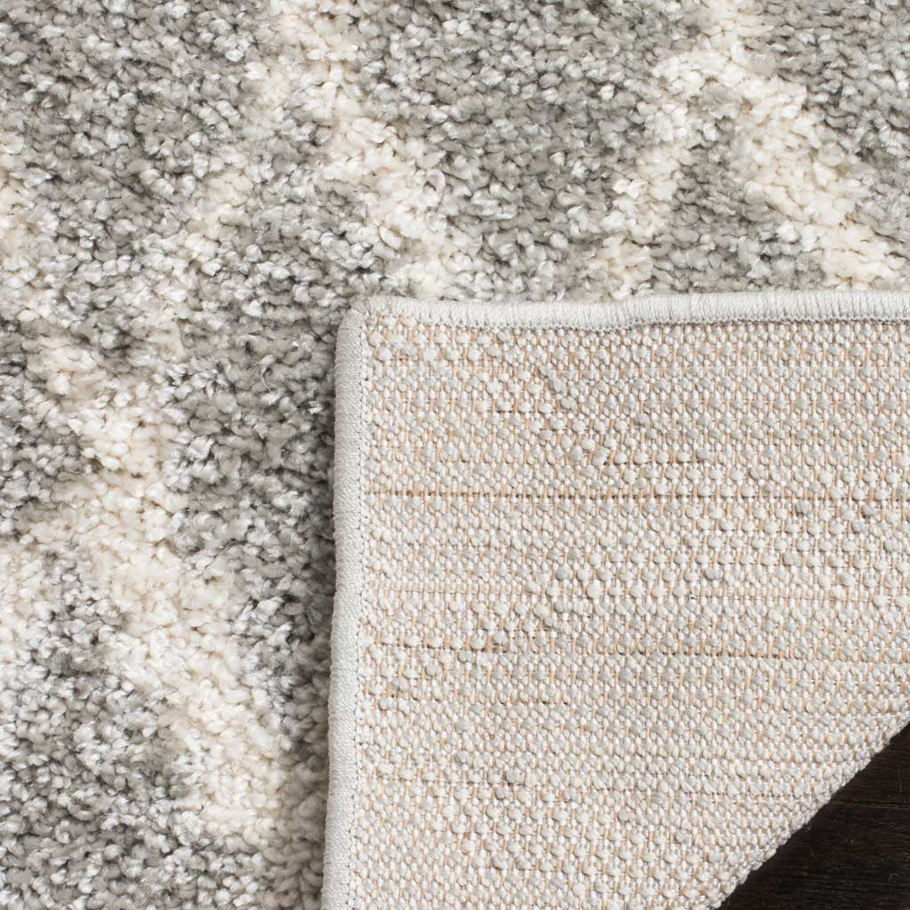 A folded corner reveals woven backing beneath the thick gray and cream shag.