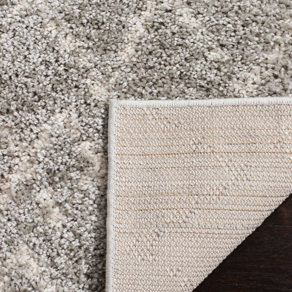 Woven backing supports the rug's plush light gray and cream shag pile