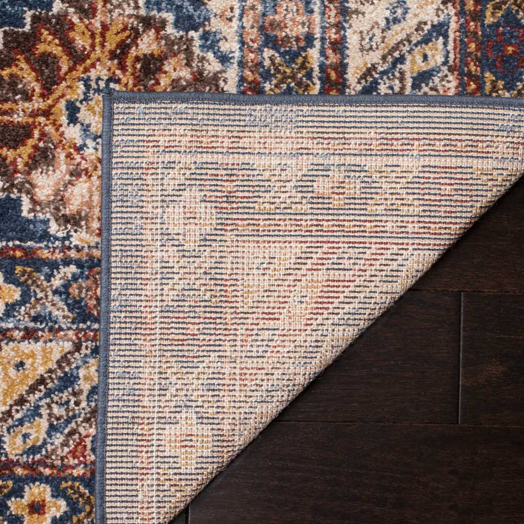 A folded corner reveals woven jute backing beneath the rug's blue, ivory and rust pattern