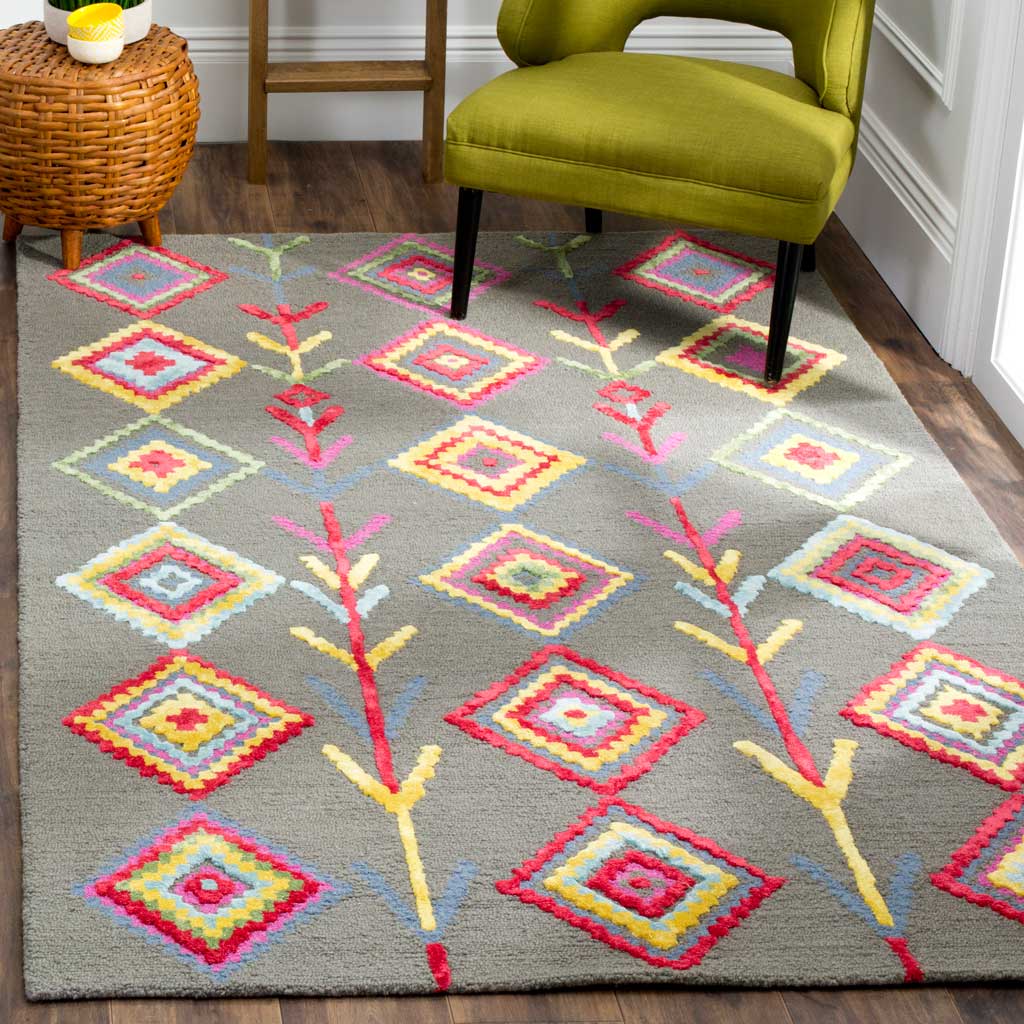 A gray rug with brilliant diamond motifs adds color beneath a green upholstered accent chair.