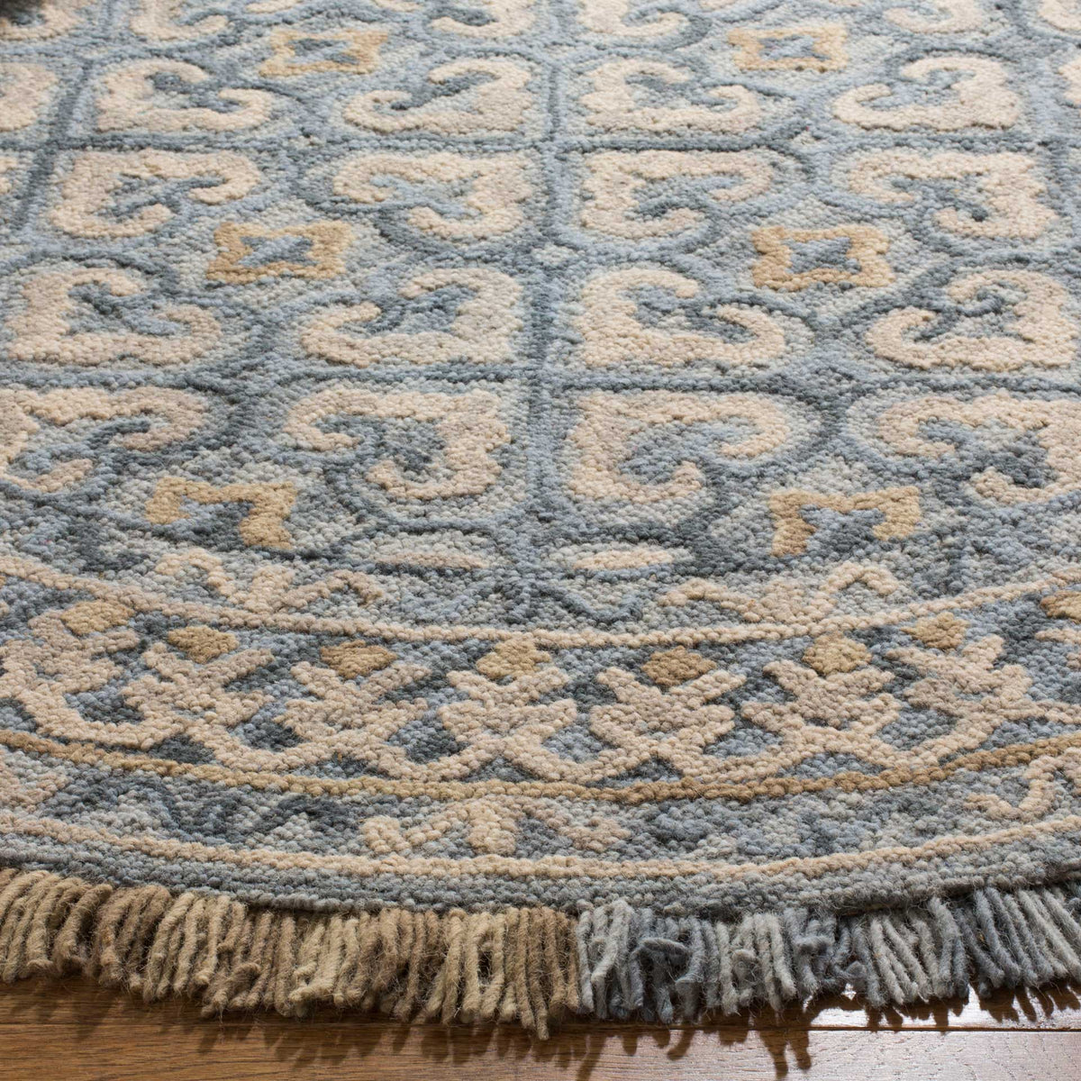 Beige and blue scrollwork meets a thick, two-tone fringe along the patterned border