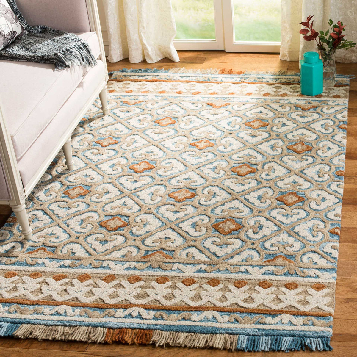 Ivory and blue scrollwork with rust accents adds lively pattern and fringed texture to a bright living space.