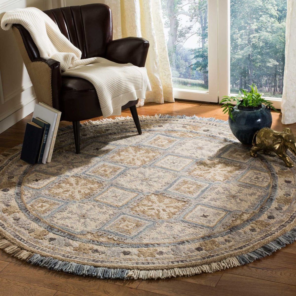 A softly patterned round rug warms a reading nook with beige florals, pale blue diamonds, and fringed edges