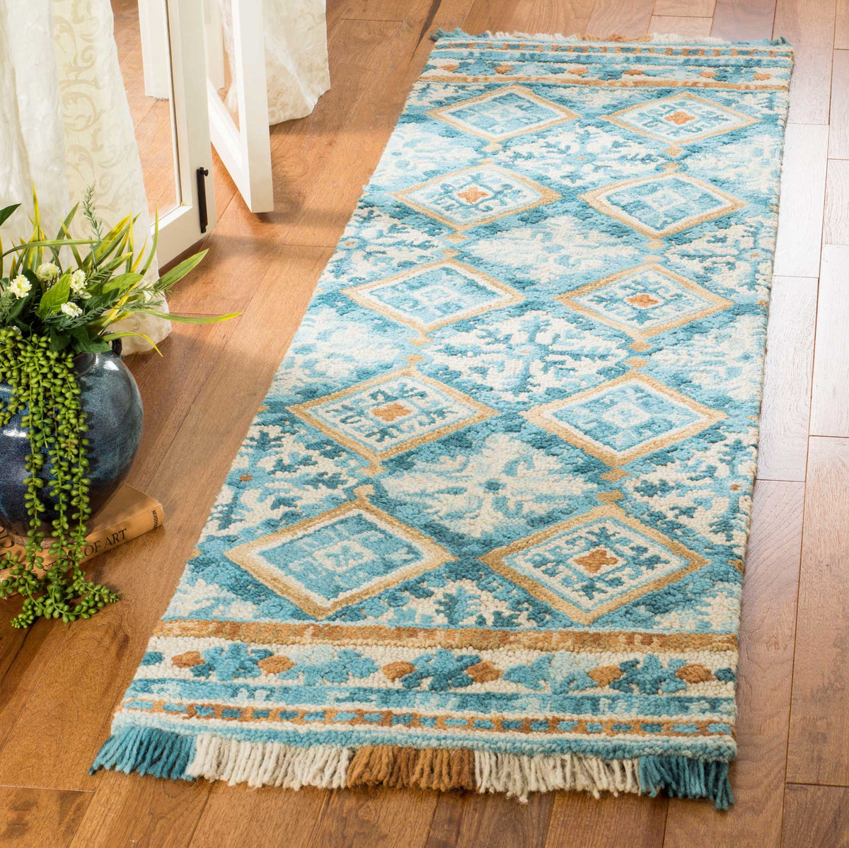 Vibrant teal and ivory runner layers geometric diamonds over floral scrollwork, with fringe at each end