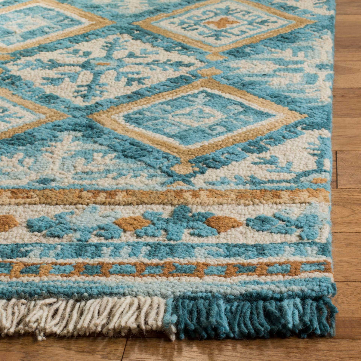 Thick teal and ivory tufting outlines diamonds above a floral border and colorful fringe.