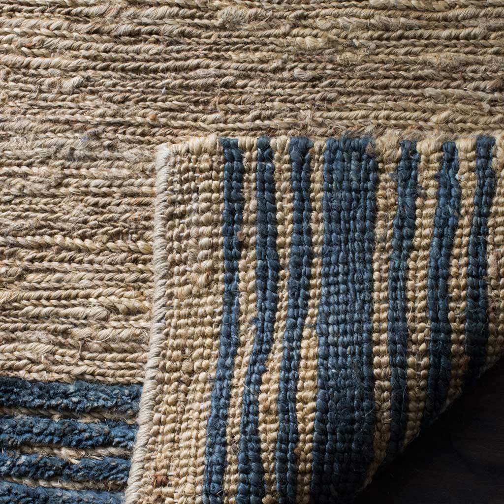 Dense natural fibers and blue woven stripes reveal the rug's textured reverse side