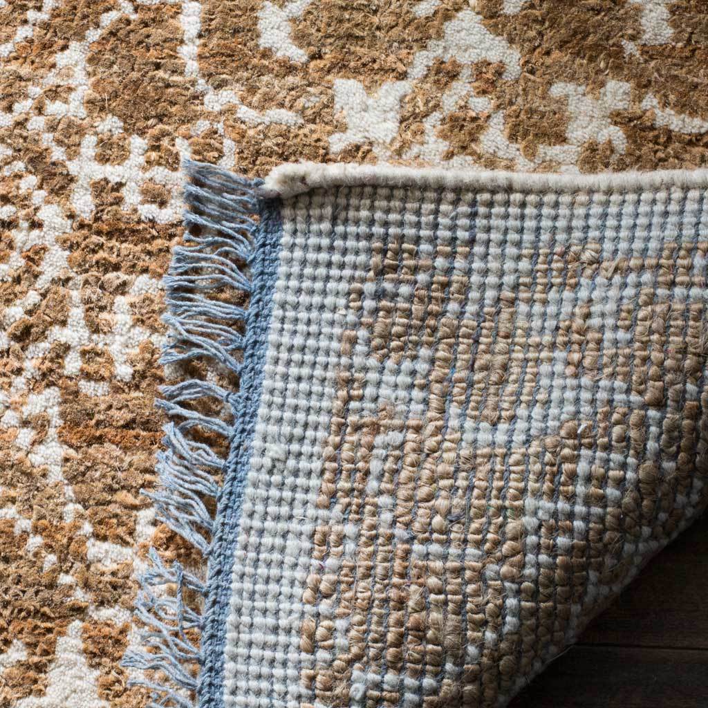 A folded corner reveals the rug's woven backing and blue-gray fringed edge