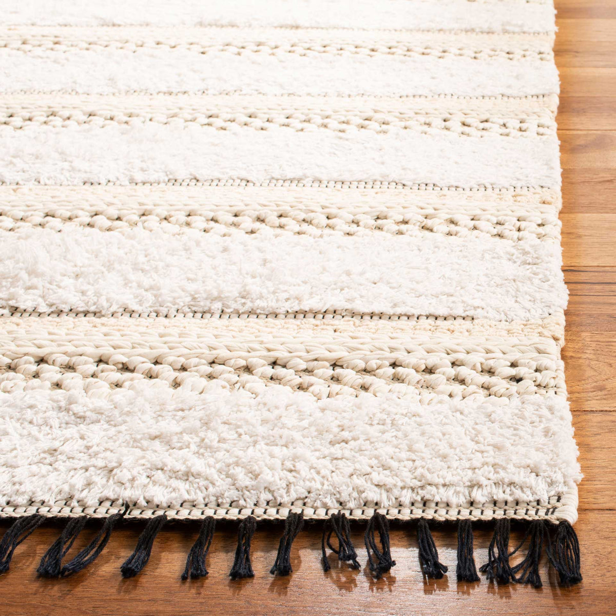 Soft ivory tufts and chunky beige stripes meet a woven edge with black fringe