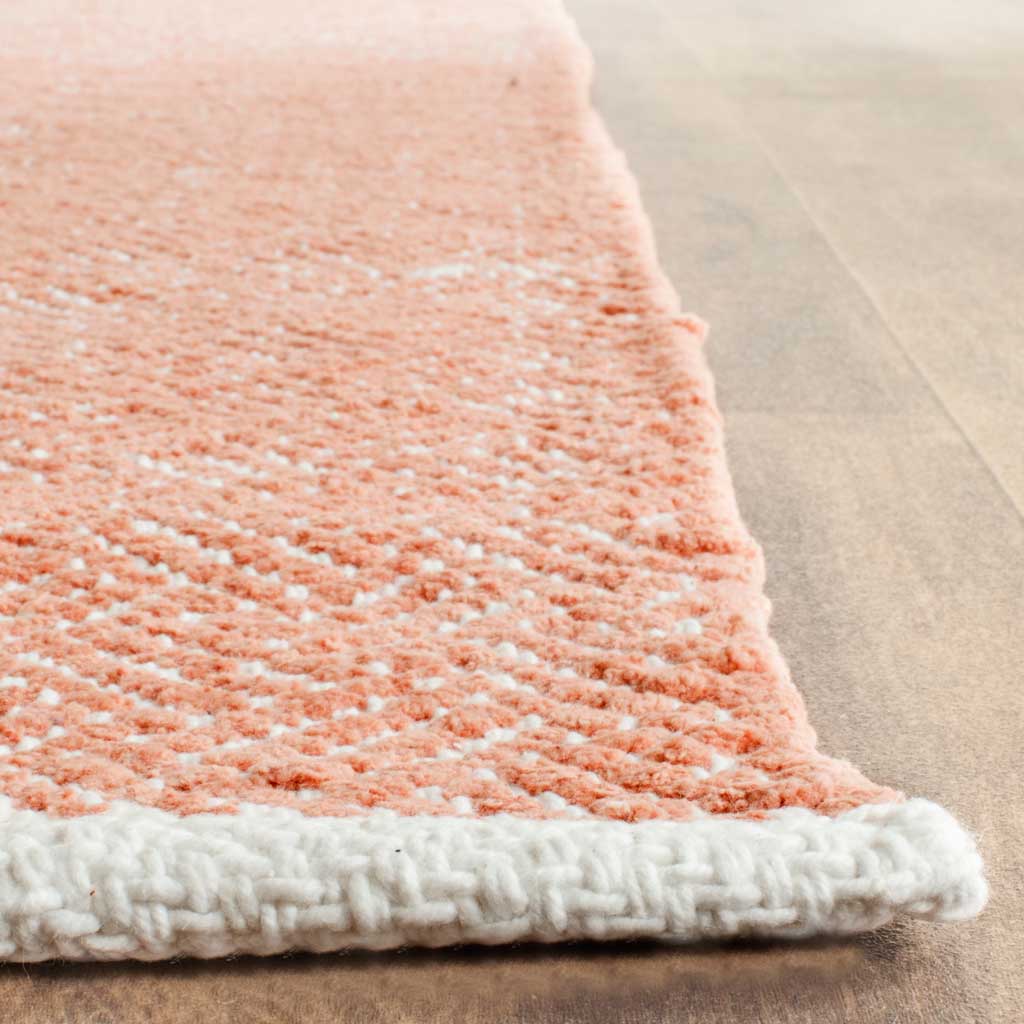 Chunky ivory binding frames the textured orange and ivory weave of this cotton rug.