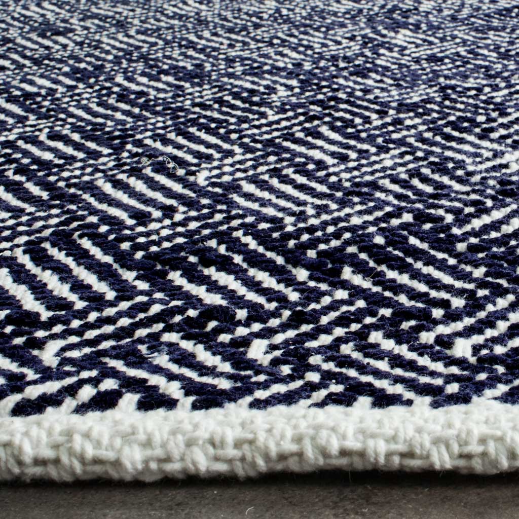 Navy and ivory woven loops stand out beside a thick ivory-bound edge on this cotton rug.