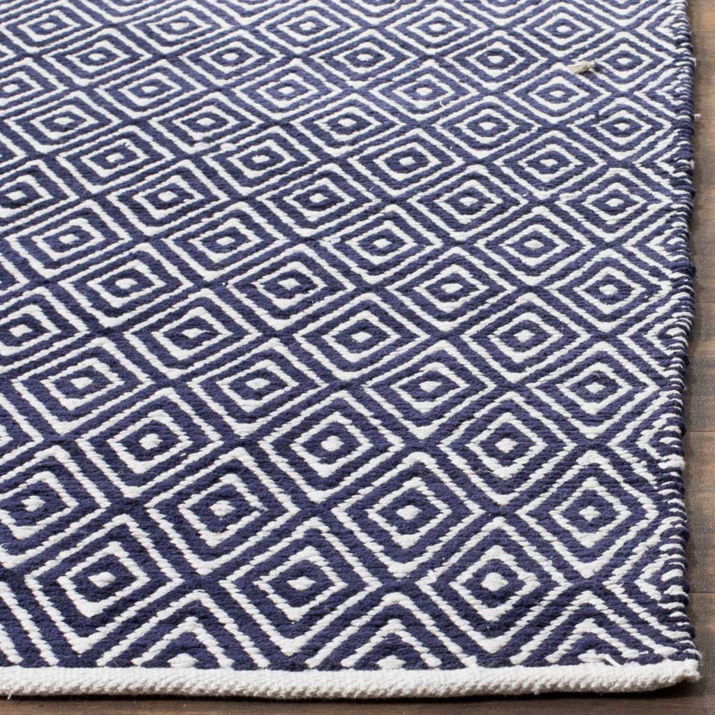 Ivory lines trace nested diamonds on navy cotton beside a tidy woven edge.
