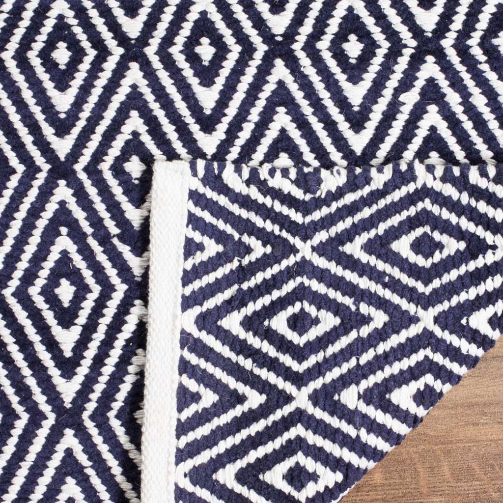 The woven reverse repeats the navy and ivory pattern beside a finished edge.