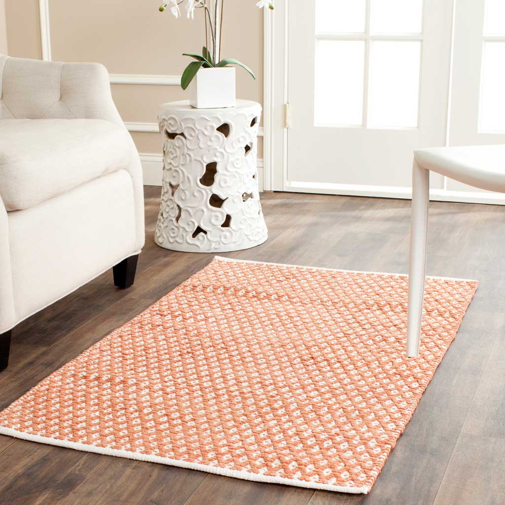 A small orange cotton rug adds a playful geometric accent beside the chair and table.