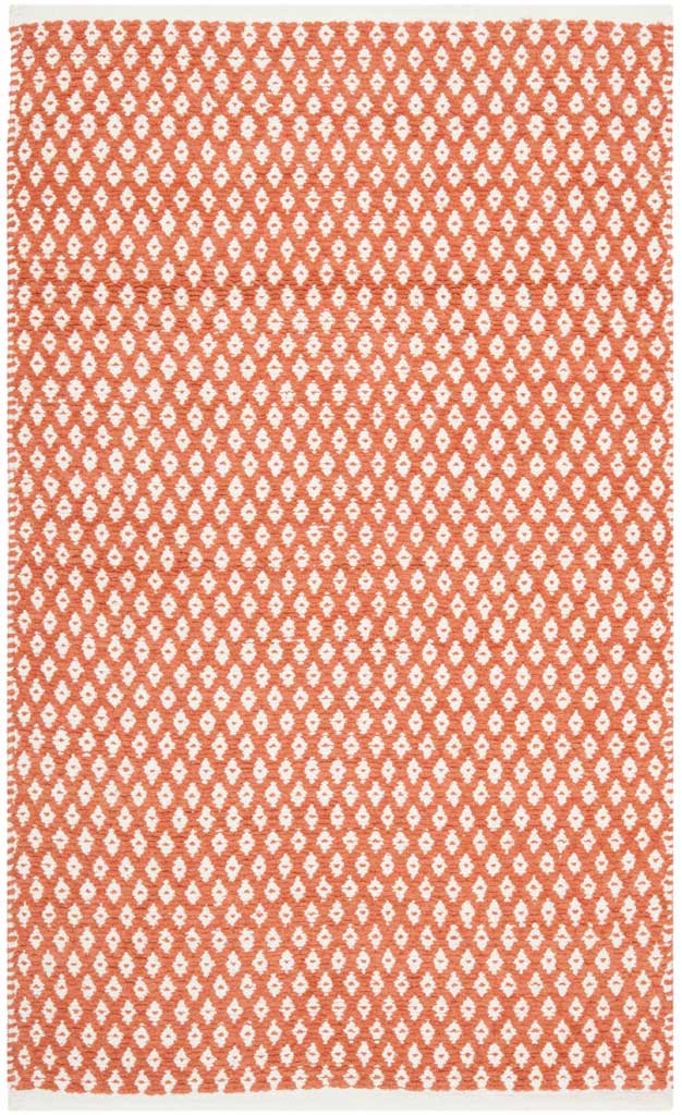 A small orange accent rug balances a bold hue with airy ivory diamond patterning.