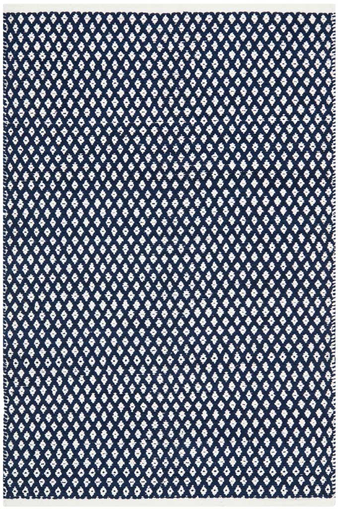 A rectangular navy cotton rug sets crisp white diamond motifs against a rich, dark ground.