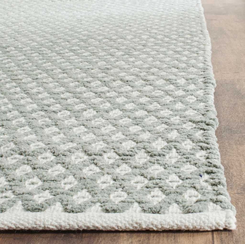 Soft gray cotton fibers and small ivory diamonds frame this rug's clean bound edge.