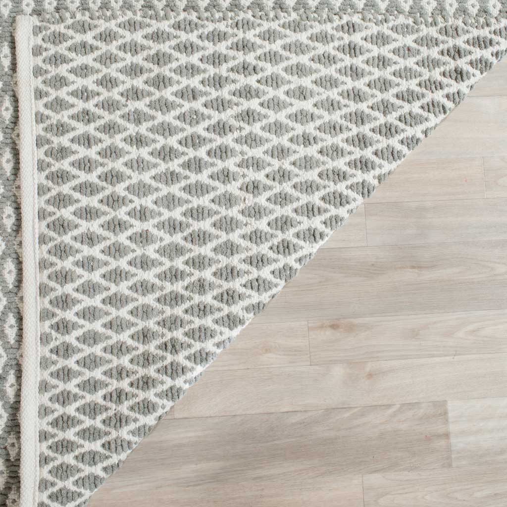 A folded edge reveals gray and ivory geometric weaving on the rug's underside.