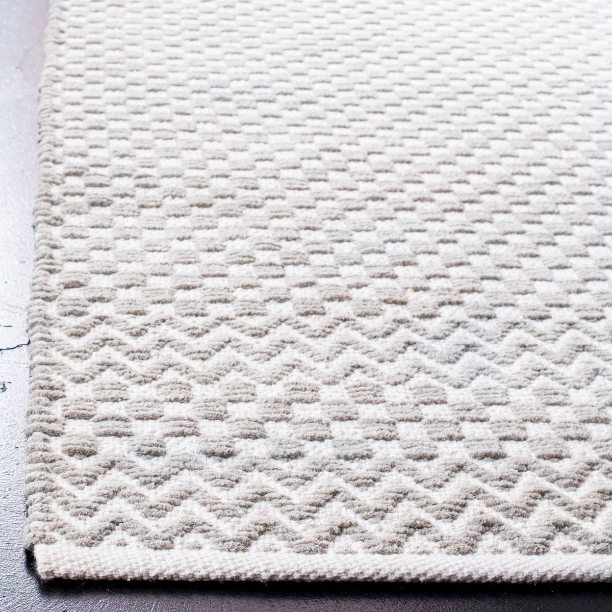 Gray cotton rug with a textured checkered weave, zigzag bands, and a neatly finished edge