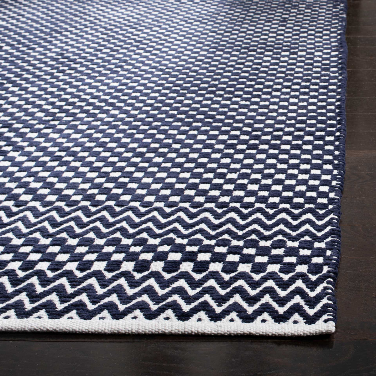 Navy cotton rug with a textured checkerboard weave and high-contrast zigzag border
