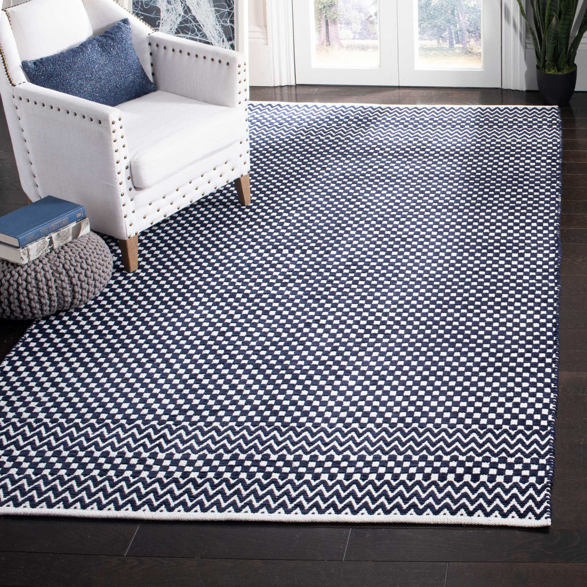 Navy and ivory geometric rug grounds a living area with checkerboard patterning and zigzag trim