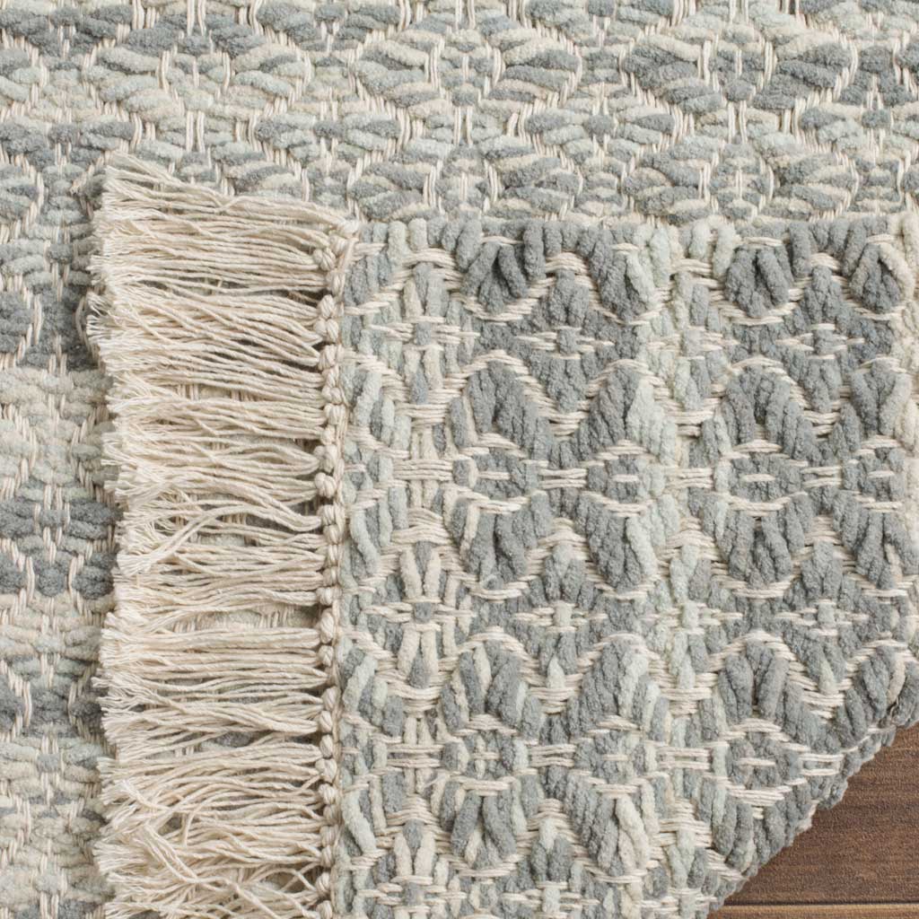 Dense gray and ivory weave continues onto the rug's reverse, trimmed with soft ivory fringe
