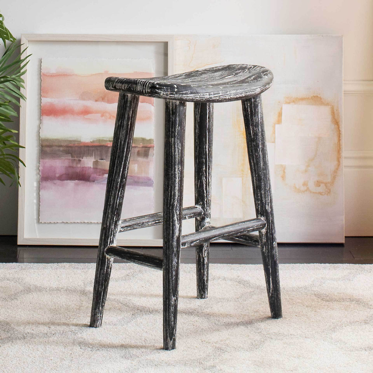 A sculpted wood seat and distressed black-and-white finish lend this counter stool rustic charm