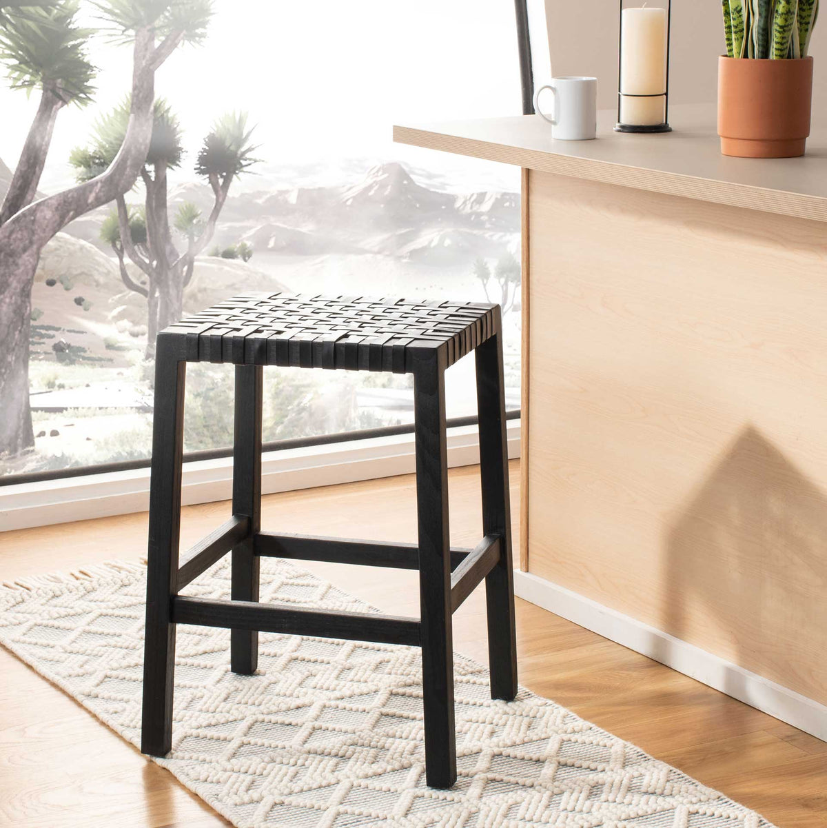 A black leather weave and slim wood legs add quiet sophistication beside a kitchen counter.