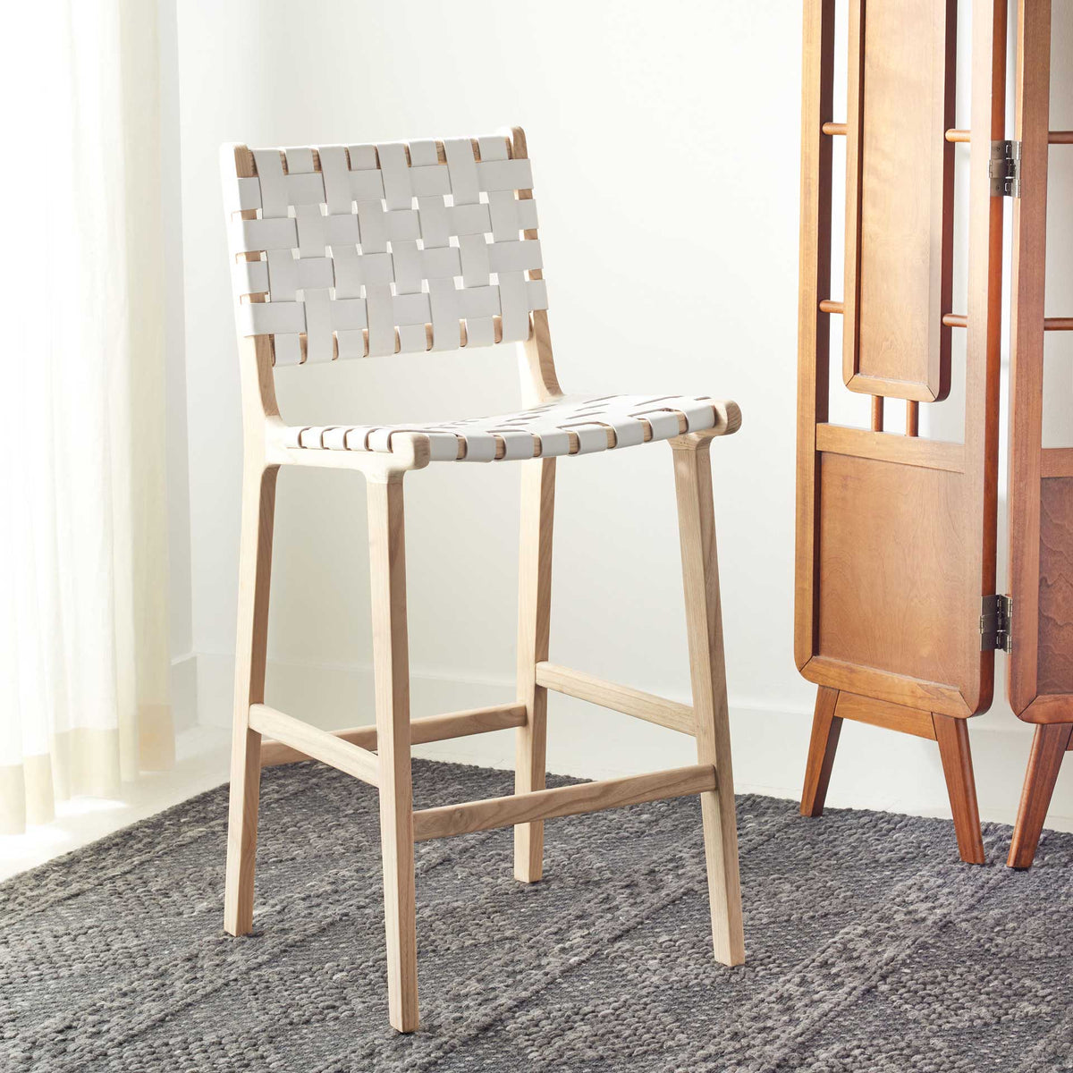 White woven leather and light wood bring a breezy touch to a cozy space with a dark rug.