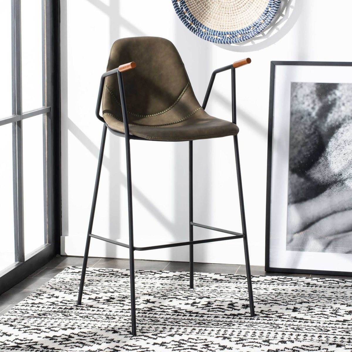 Olive faux leather barstool features a stitched seat, wood-tipped arms and open black metal legs