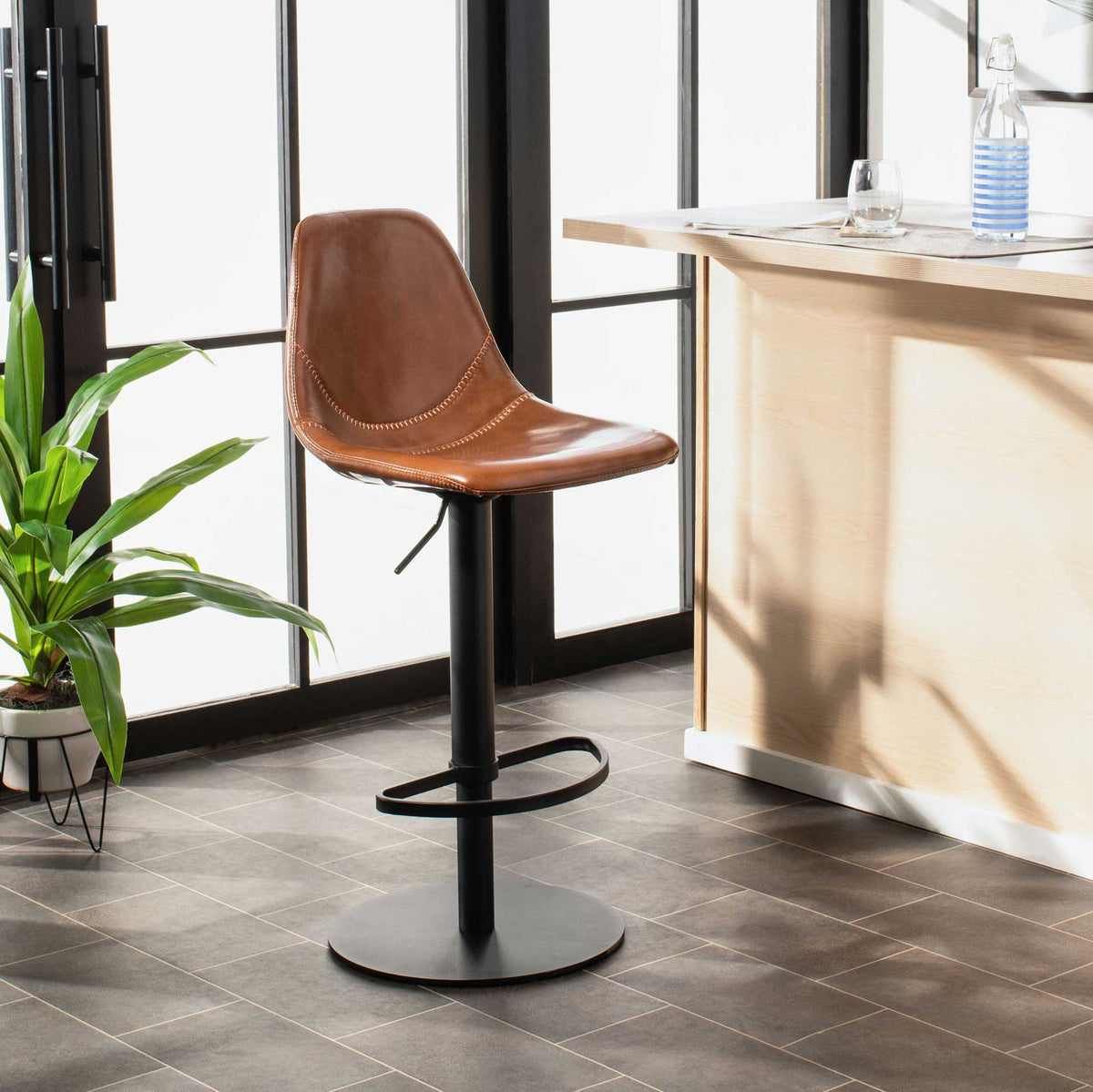 Warm cognac faux leather and a black pedestal add modern style beside a light wood counter