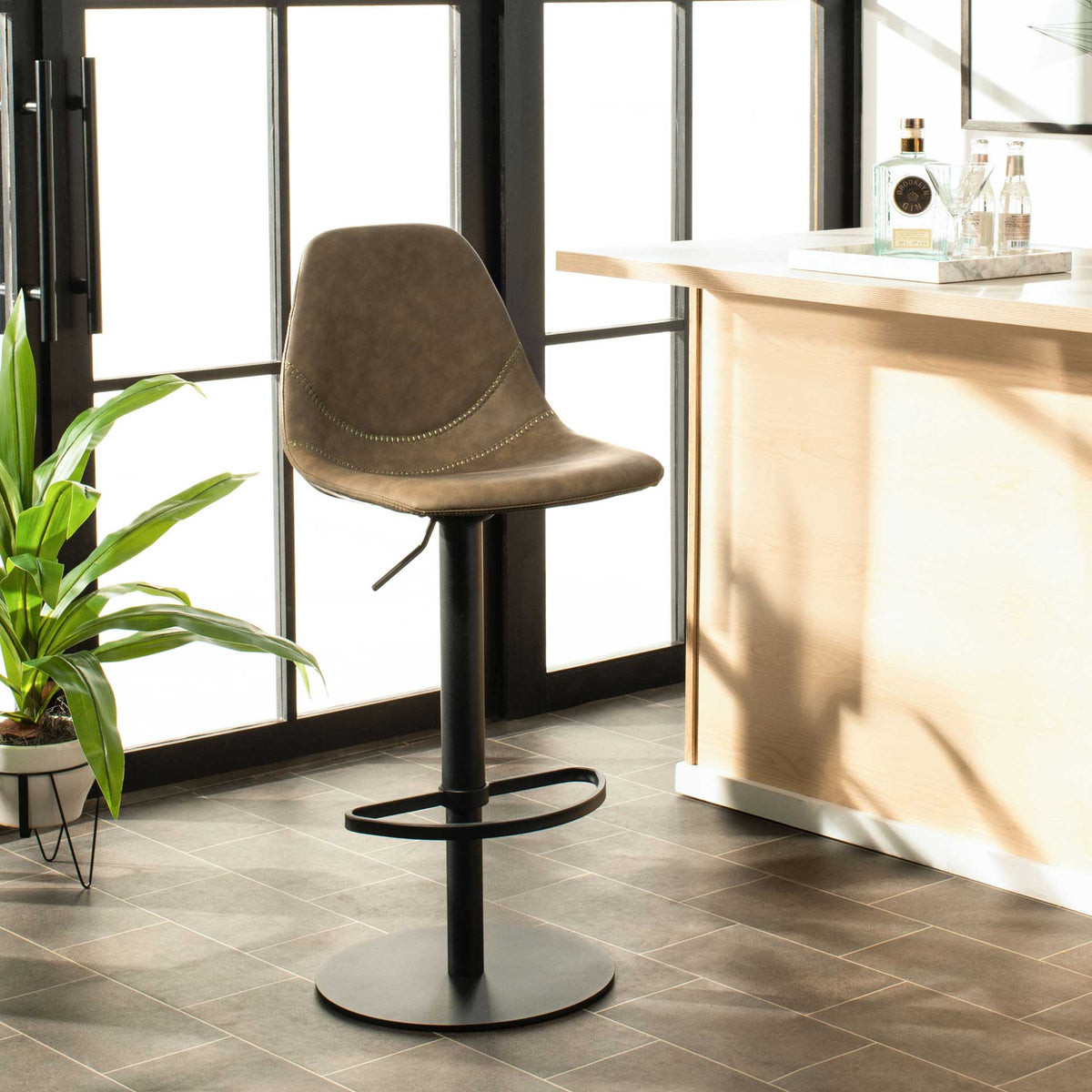 Olive faux leather seat and a sleek black pedestal complement a modern kitchen counter