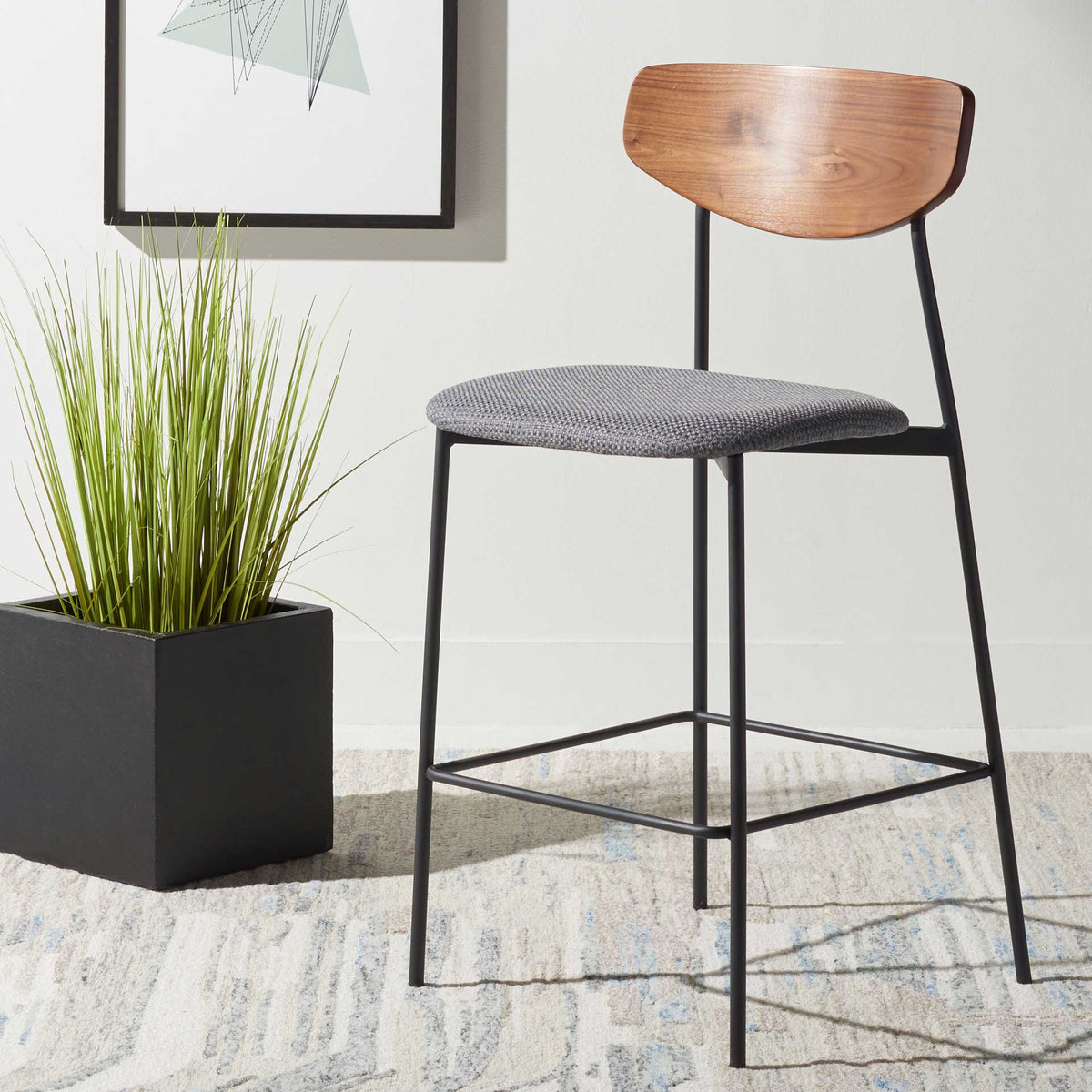 Walnut backrest and gray fabric seat bring warm texture to this black iron counter stool