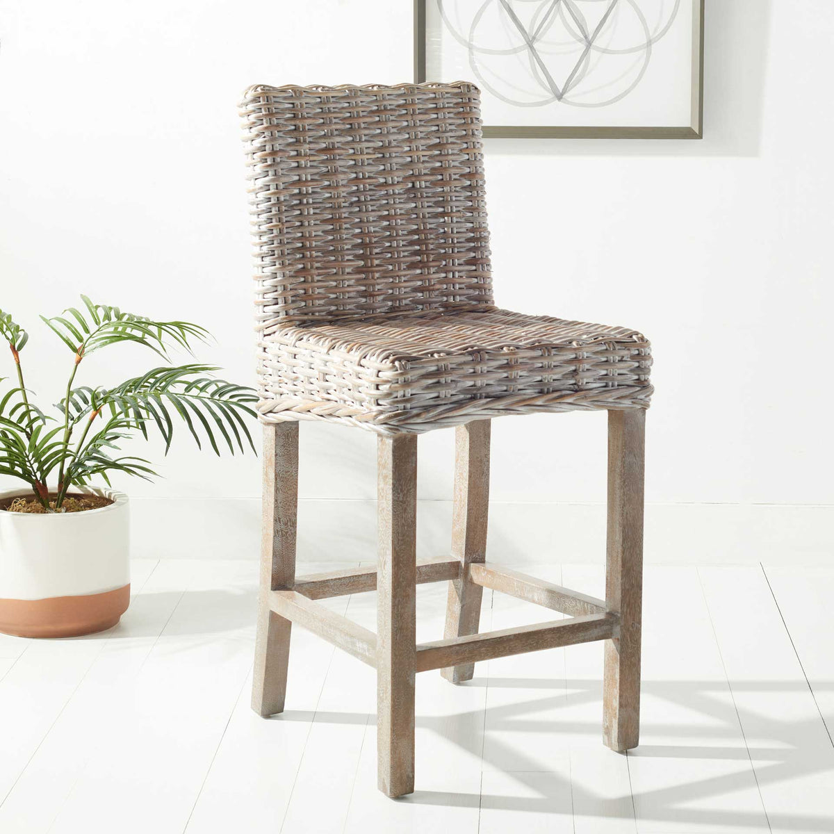 Whitewashed wicker counter stool lends a breezy touch beside a potted plant